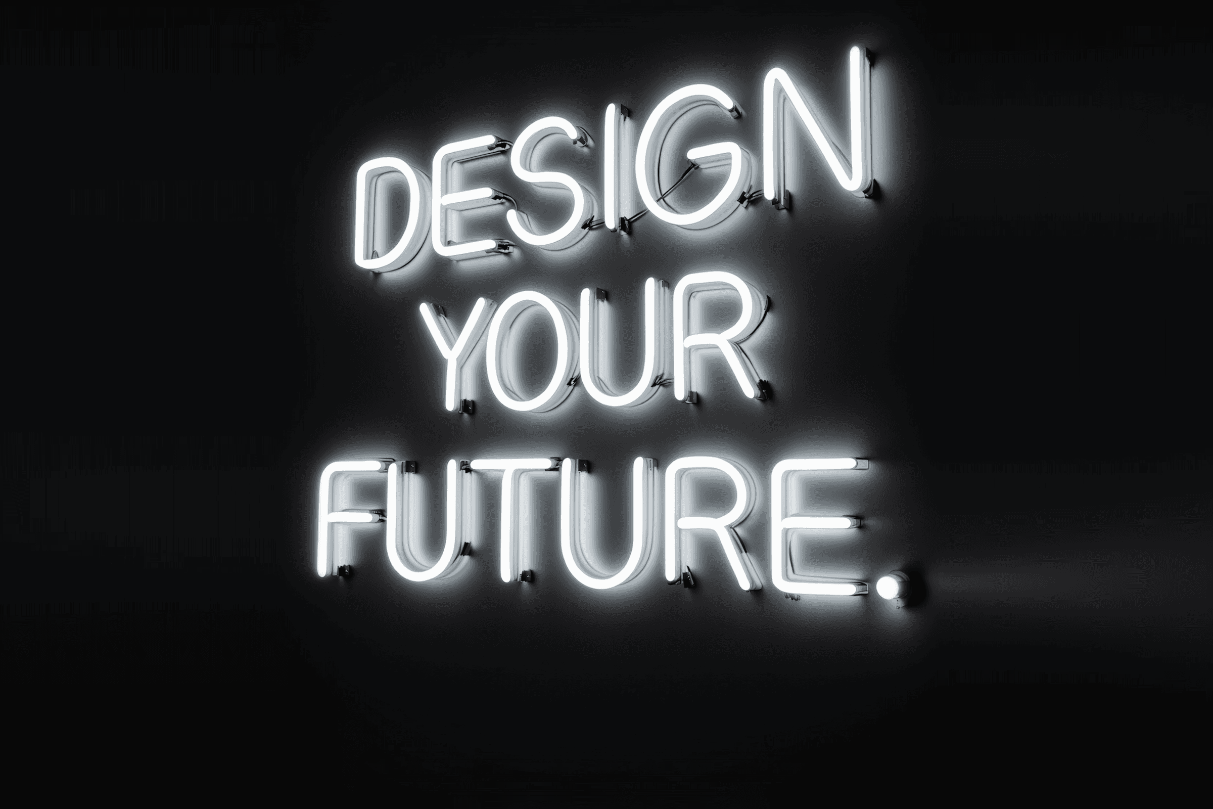 Glowing white neon sign reading "DESIGN YOUR FUTURE" on a black wall, representing the necessity of design-led strategies for modern startups.