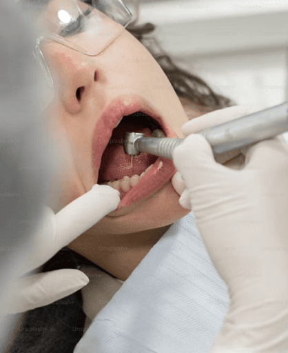 Ein Zahnarzt untersucht den Mund eines Patienten mit einem zahnärztlichen Instrument, während er Handschuhe und eine Schutzbrille trägt.