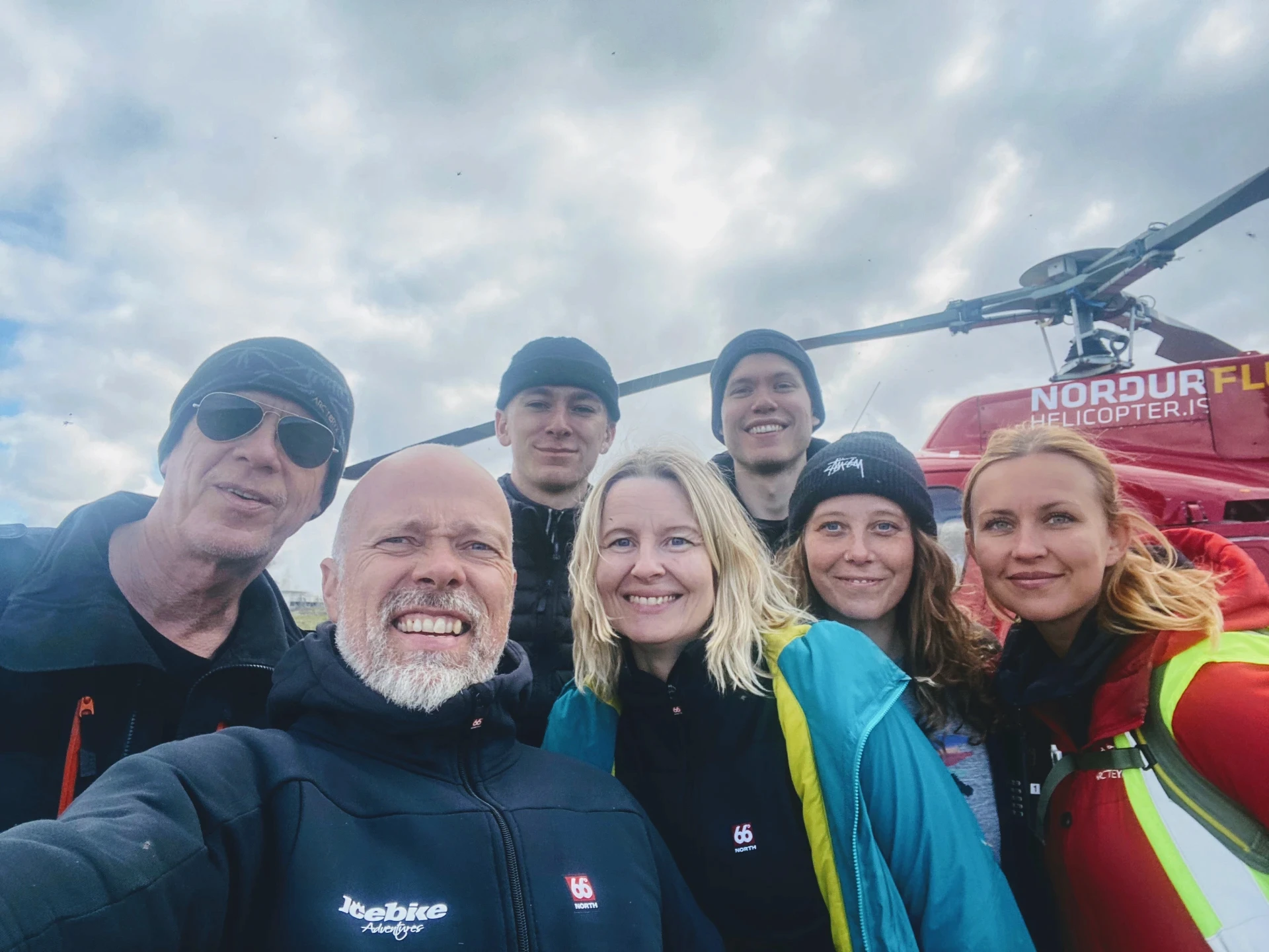 People smiling in front of a helicopter 