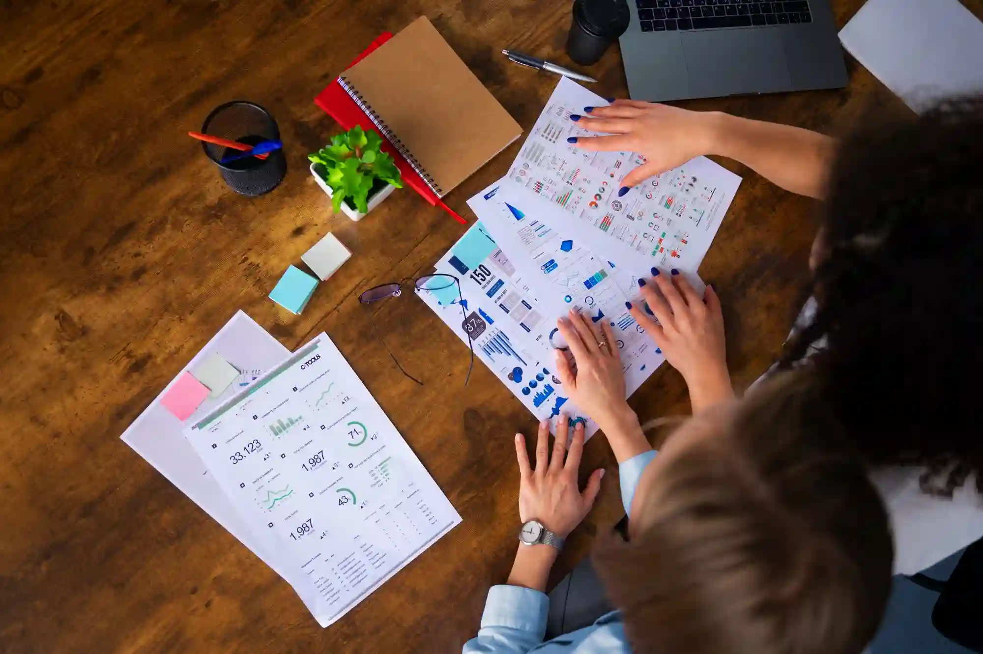 Overhead view of two people reviewing business data charts together.