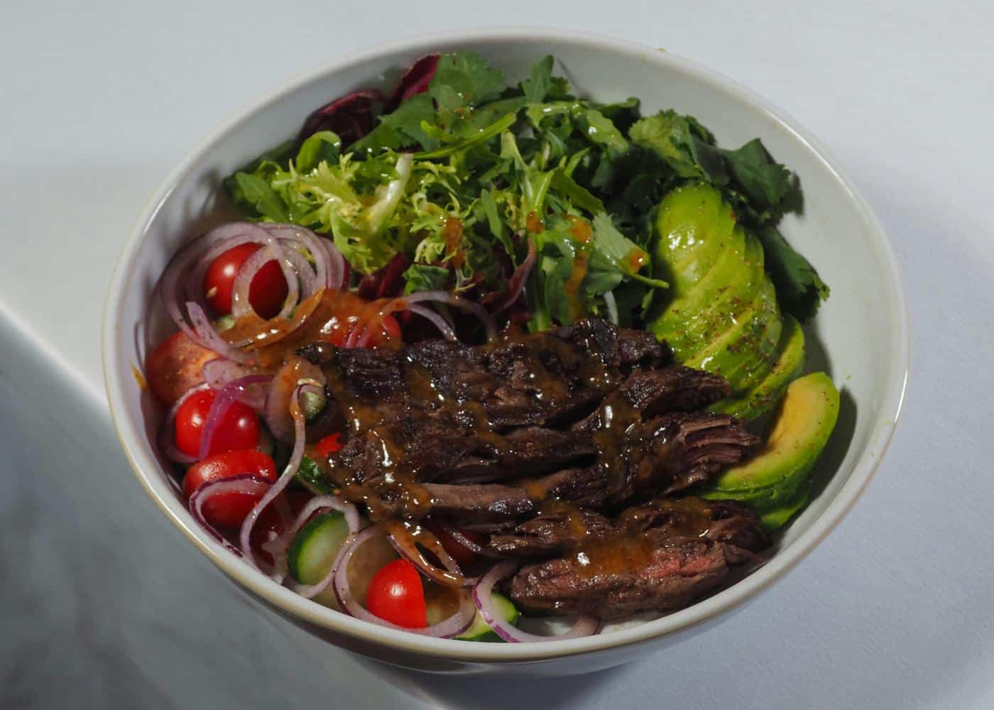 Bowl showing an example of the keto diet with steak, lettuce, veggies and avocado