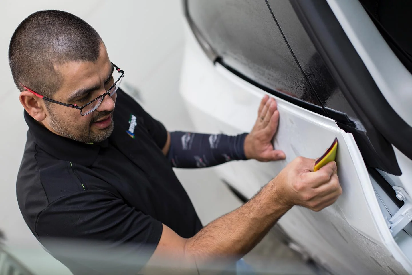 Detailer applies car film with a squeegee.
