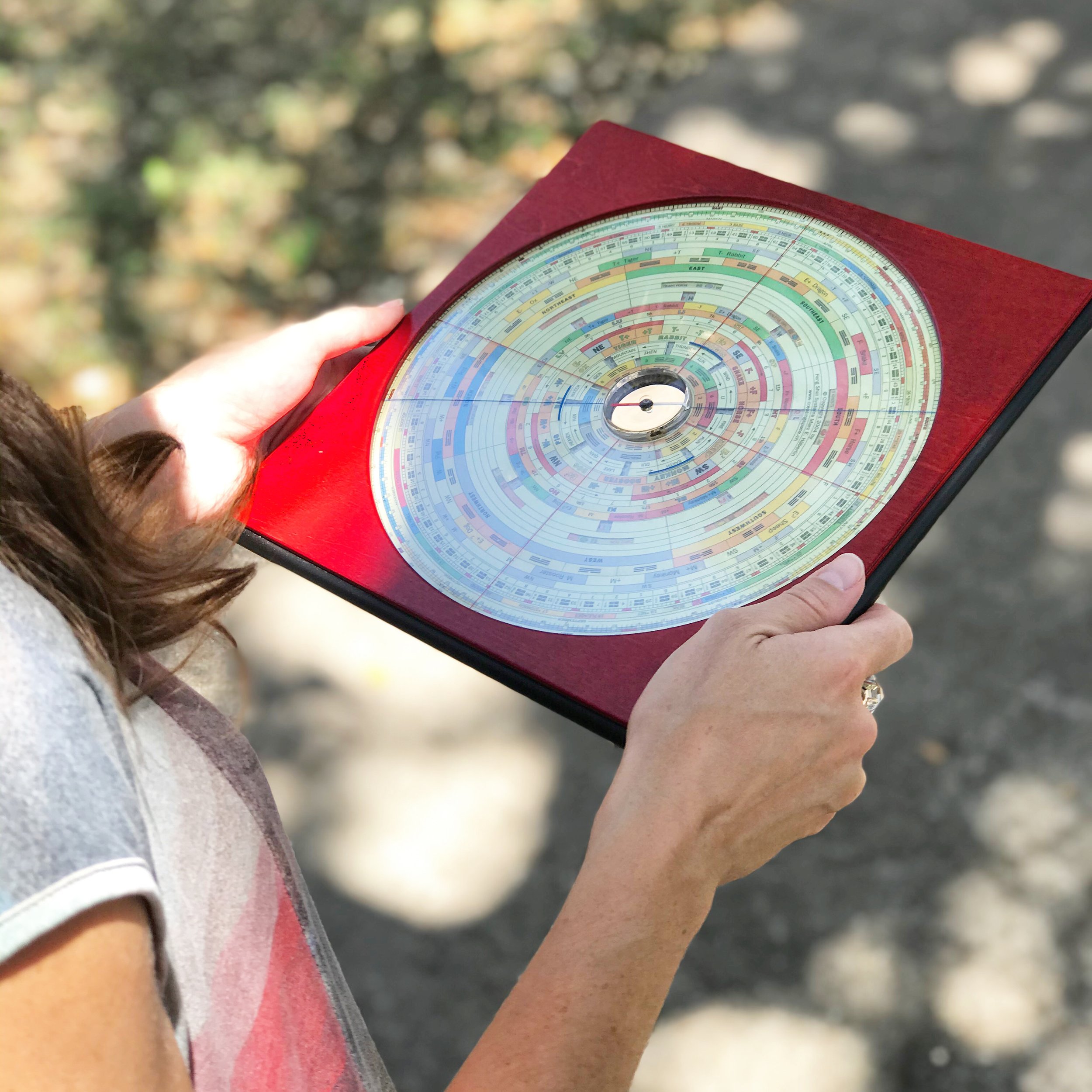 A person holding a red feng shui compass