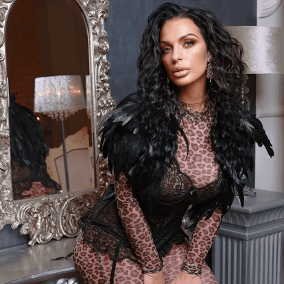 Mujer con top blanco sin tirantes posando en un parque bajo la luz del sol con árboles al fondo.