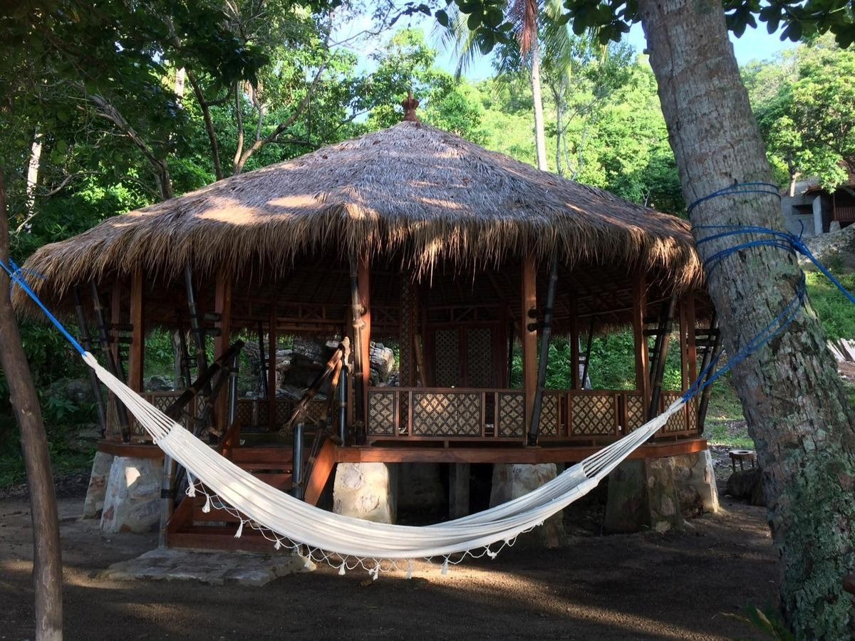 Wooden gazebo with thatched roof and a white hammock.