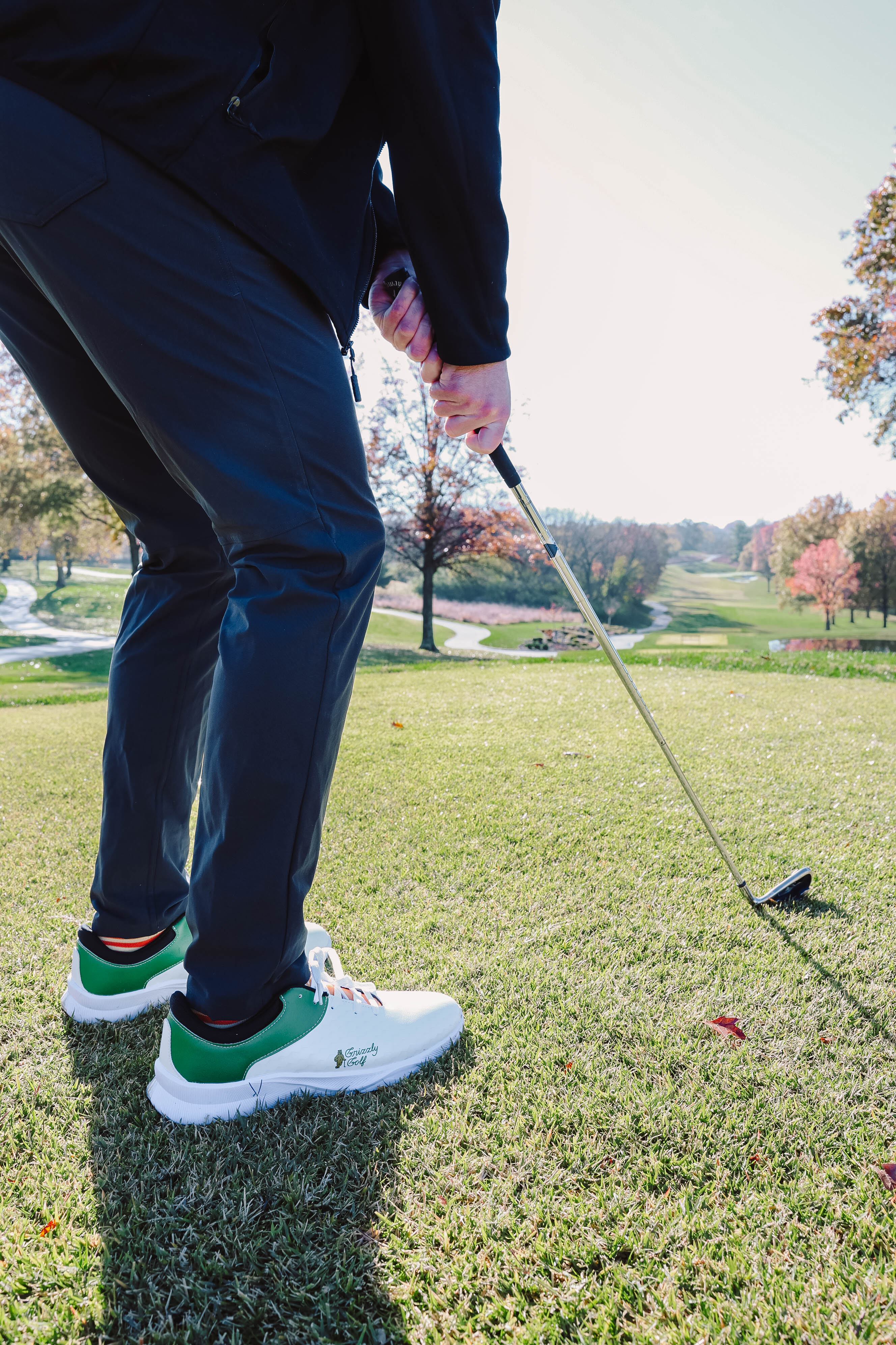 An upclose shot of custom golf shoes on a person who is about to hit a golf ball.