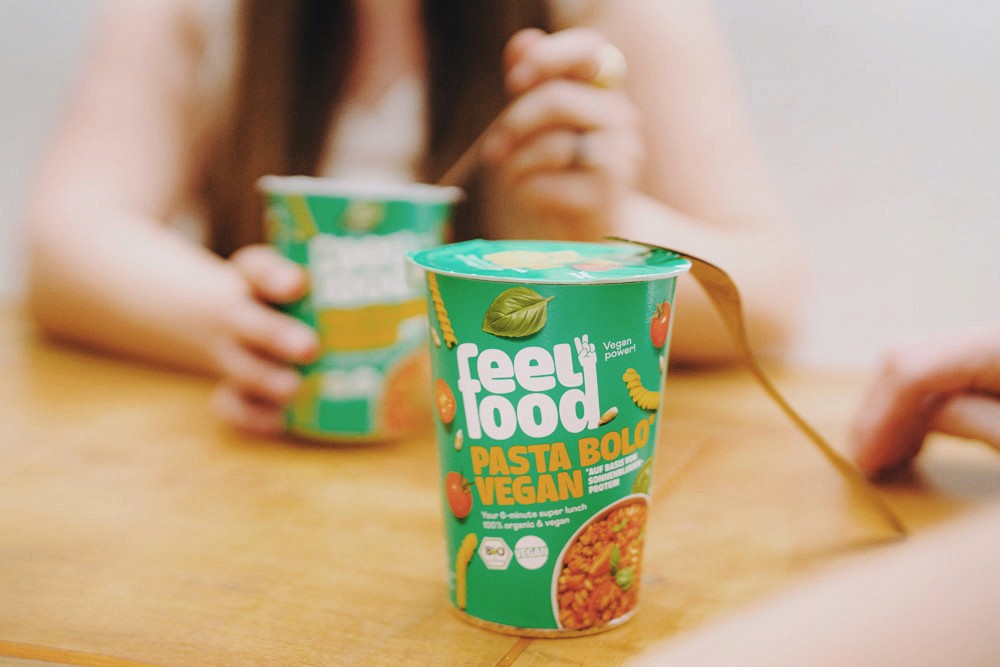 Frau isst feelfood Packung im Vordergrund