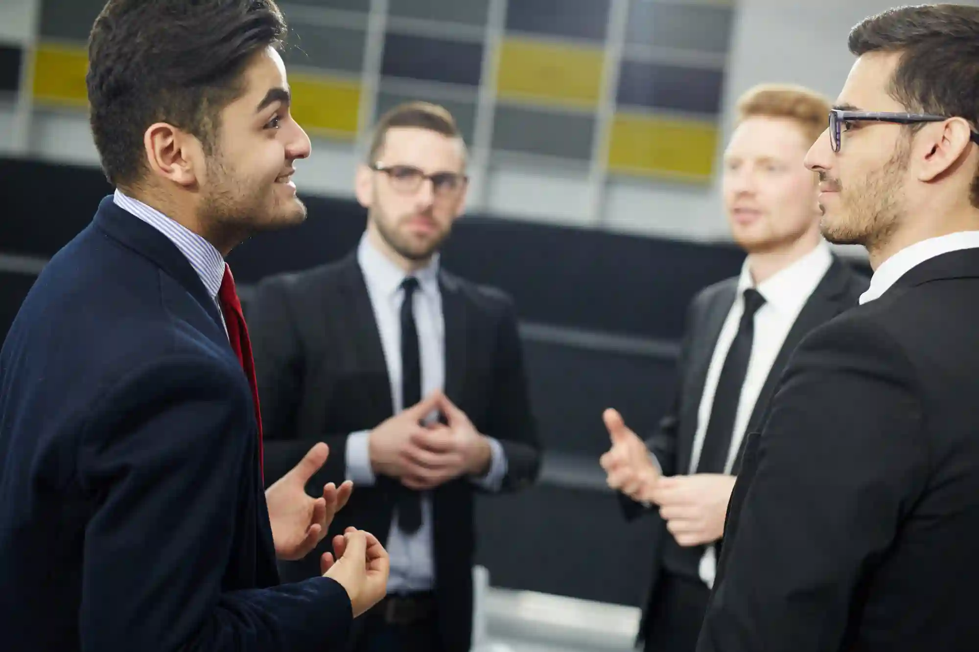 Diverse businessmen engage in a professional discussion, highlighting the importance of networking and effective communication in corporate environments.