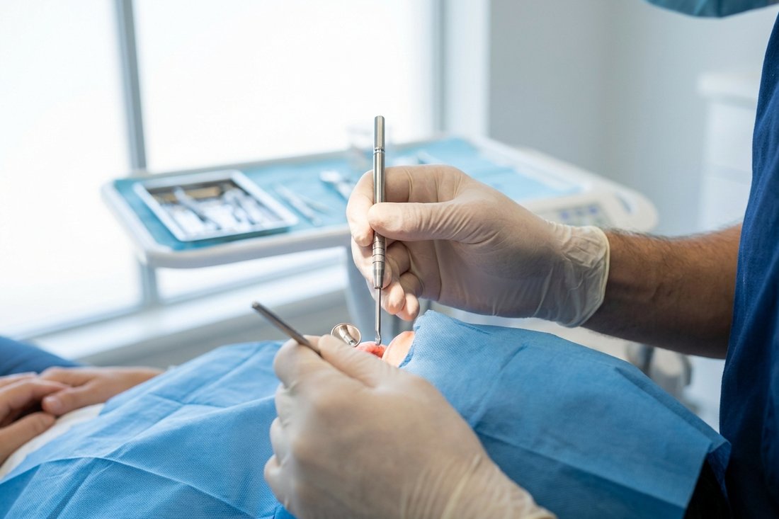 Dentist's gloved hands using precision instruments during dental implant surgery