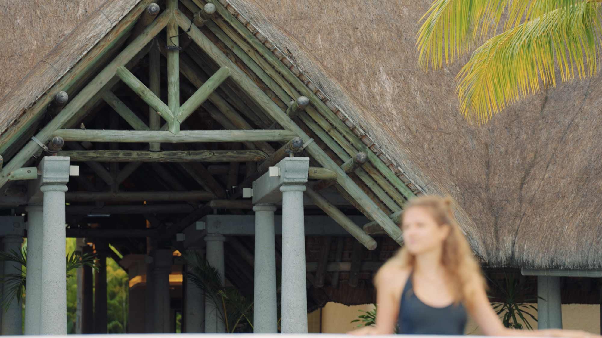 Blurred woman in front of rustic building; filmproduction ad for a hotel in mauritius