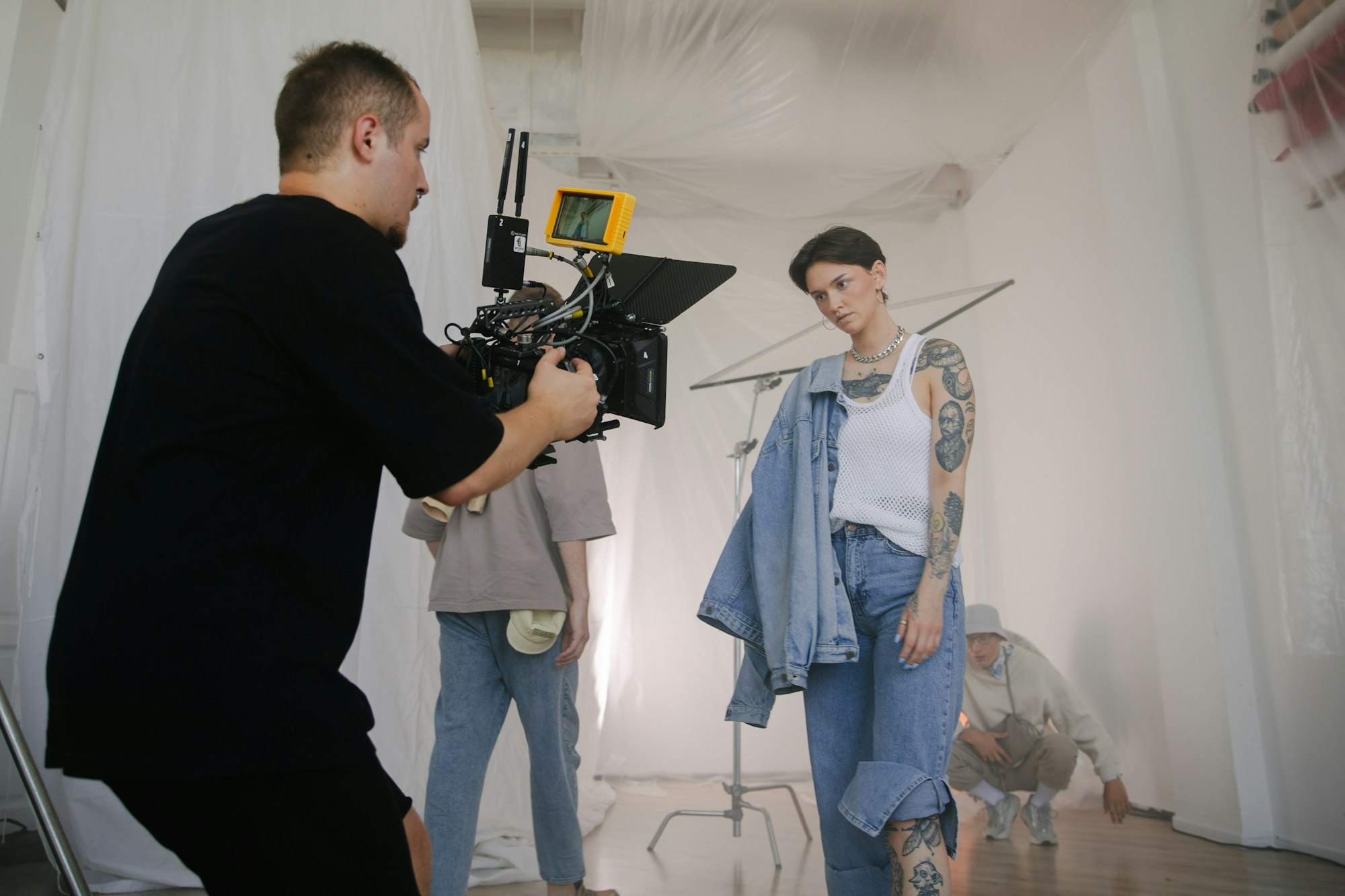 A camera operator films a model in a denim jacket on a fashion video shoot