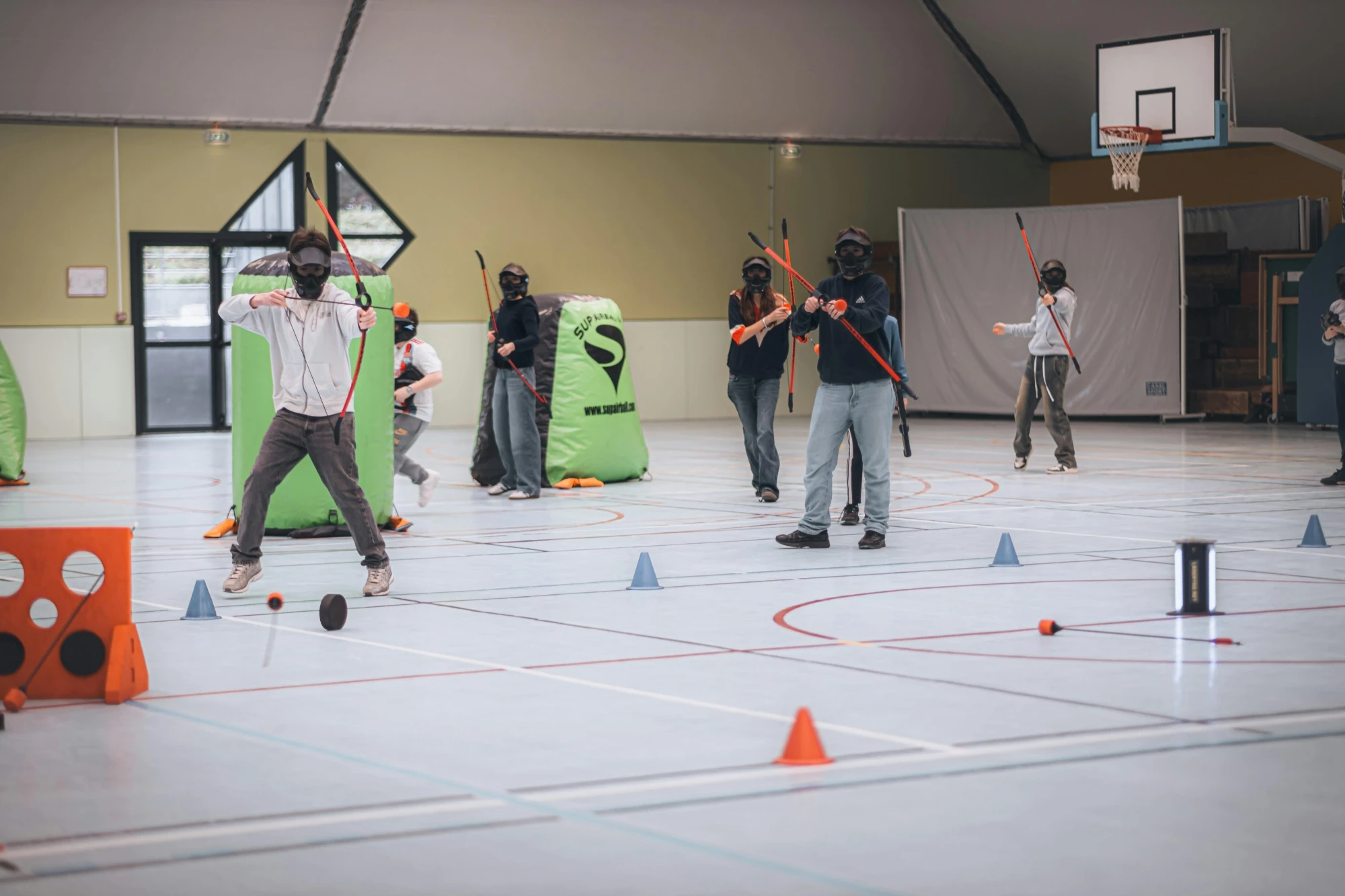 A group of people engaged in a game inside a gym, showcasing teamwork and active participation.