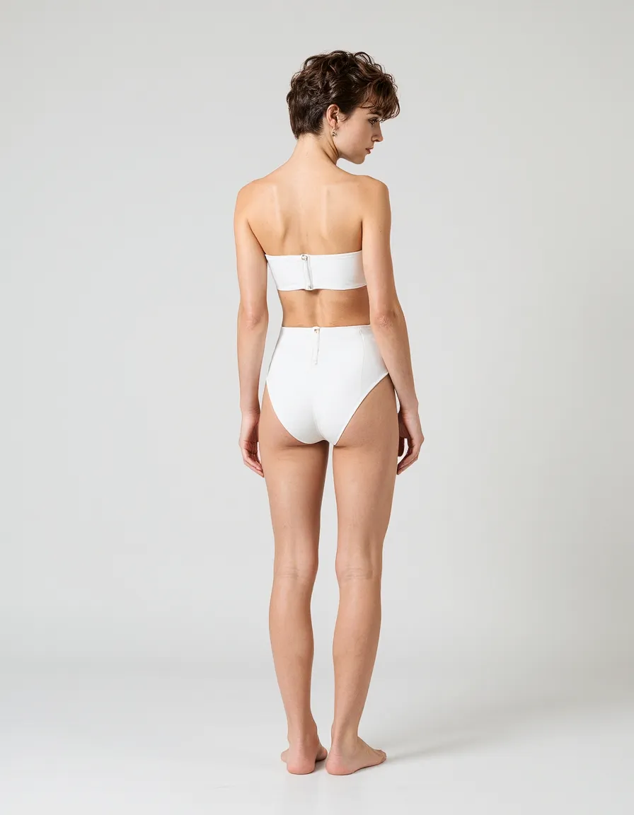 Back view of white two-piece swimsuit featuring bandeau top and high-waisted bottoms against minimal light background