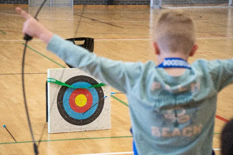 A child celebrates hitting an archery target