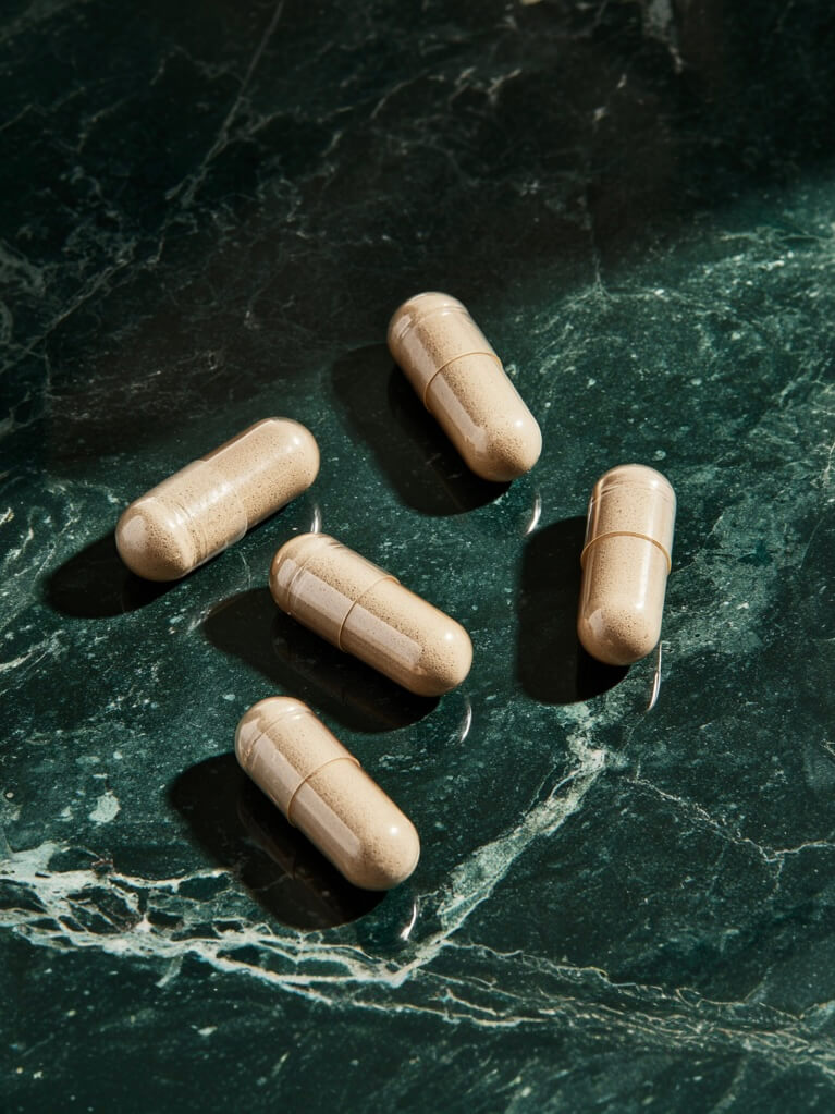 Five beige capsules sitting on a green marble countertop