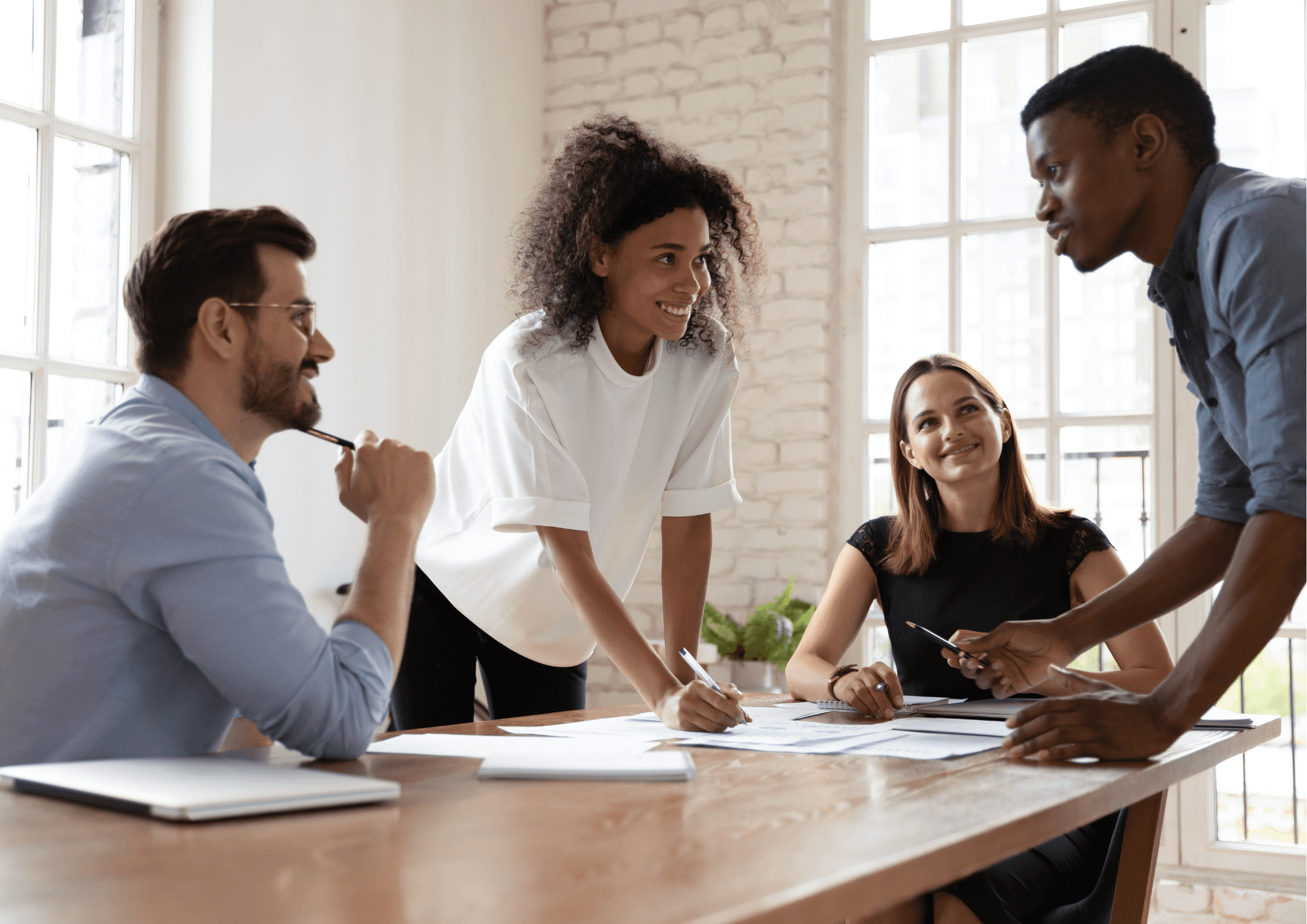 A diverse group of professionals collaborates around a table in a modern office, exchanging ideas and fostering teamwork to achieve shared goals.