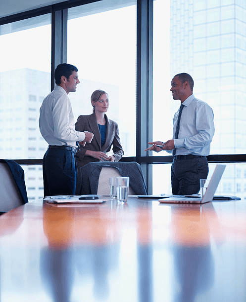 Man gesturing while speaking to colleagues in a sunlit office.