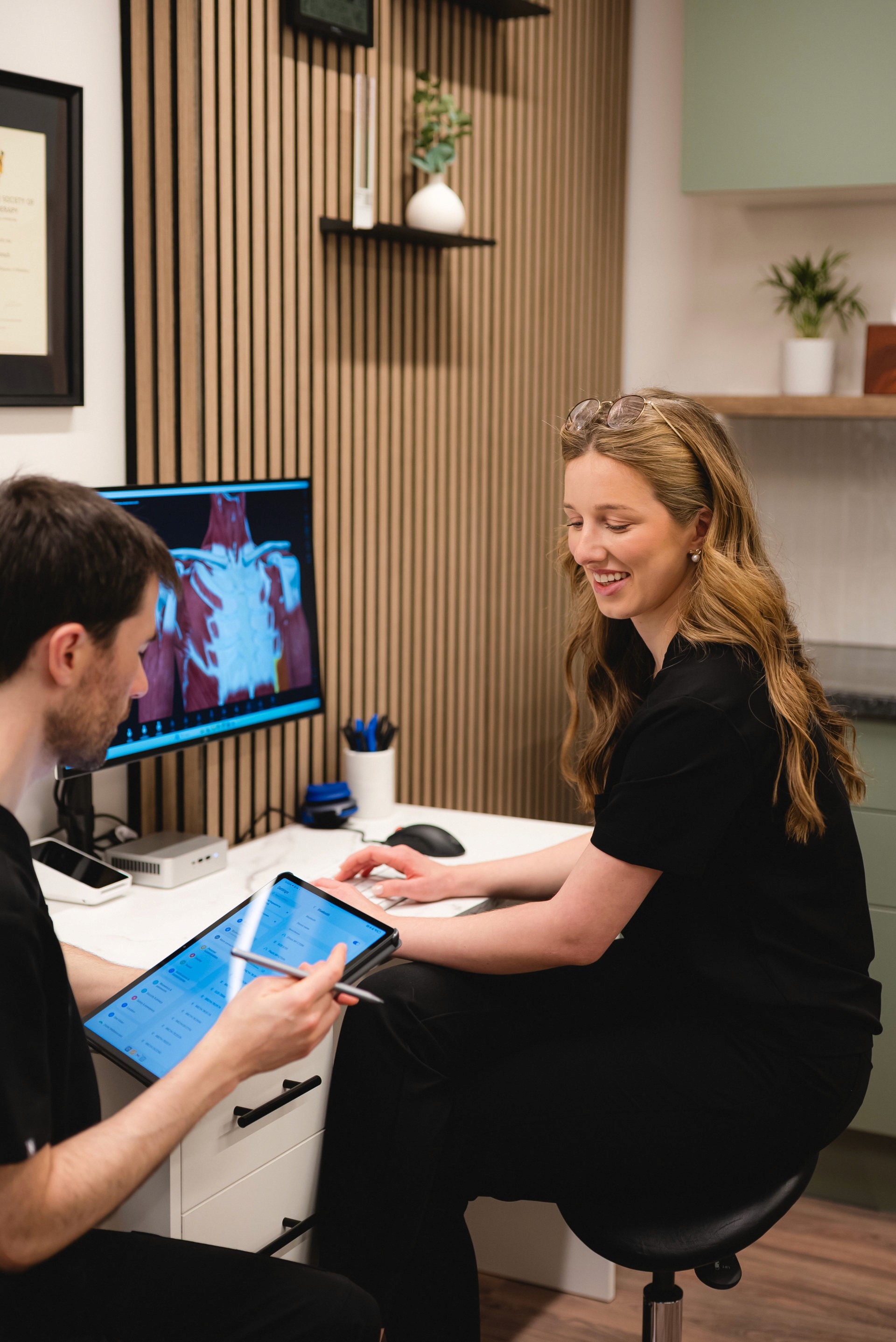 Two physiotherapists sitting at a desk discussing a case