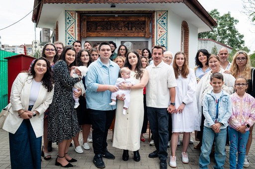 Fotografie de grup cu familia și nașii la finalul botezului.