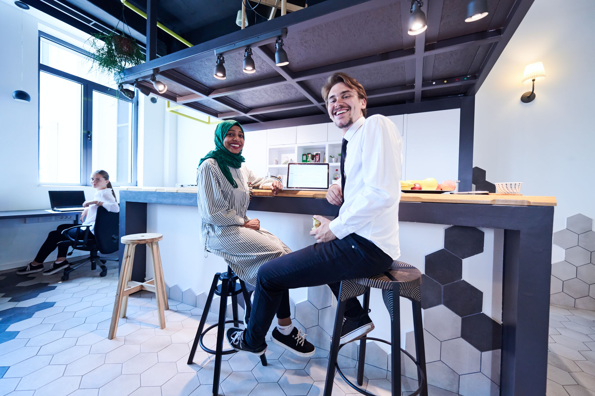 A man in a white lab coat working at a computer, viewing a 3D model on the screen in a laboratory or office setting.