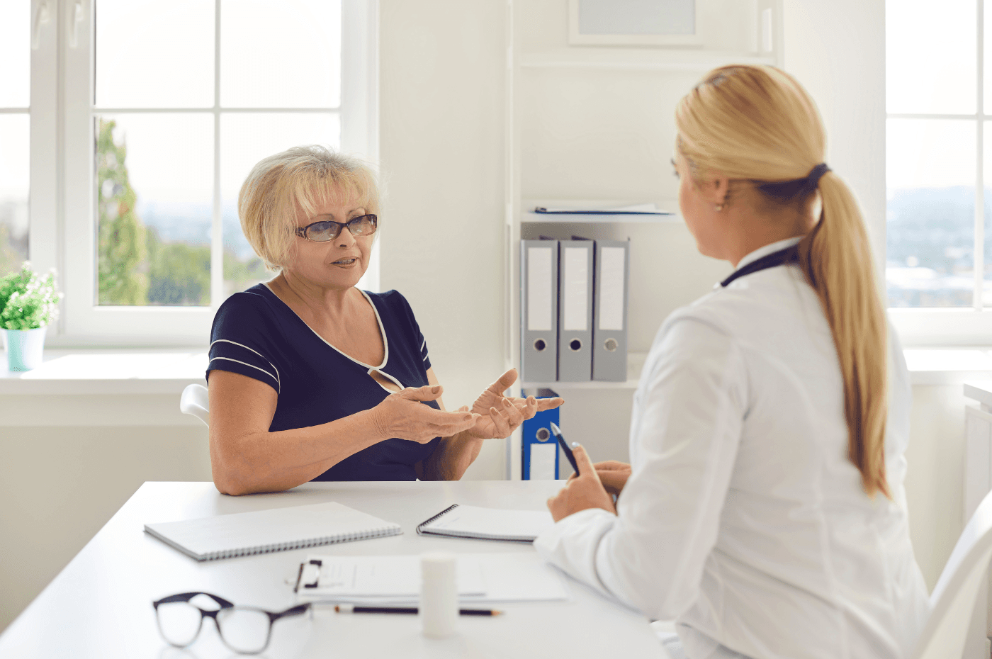 Mature Positive Woman Patient Sitting and Talking to Young Woman Doctor