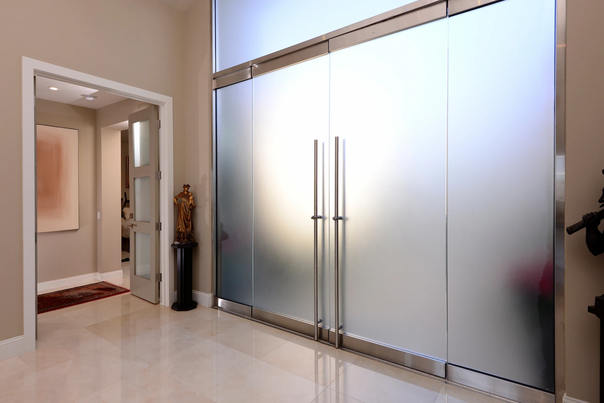 Harbor Ridge Transitional Remodel's elegant entryway with crema marfil marble and frosted glass doors.