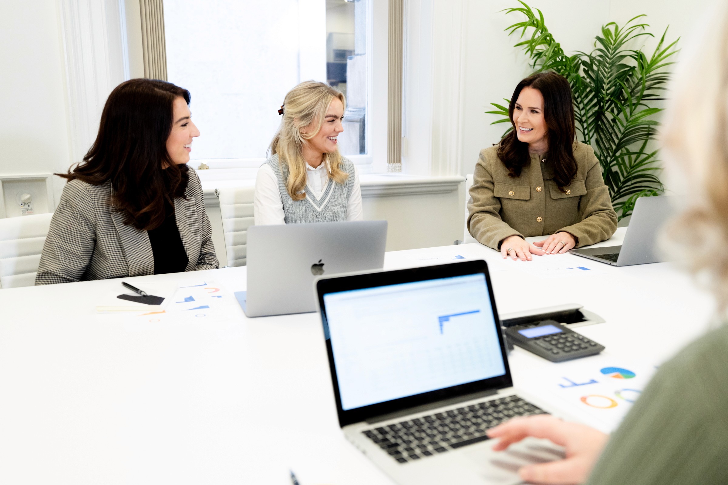 Three members of the Grow Web team engaged in a discussion around a conference table, with laptops and charts in front of them.