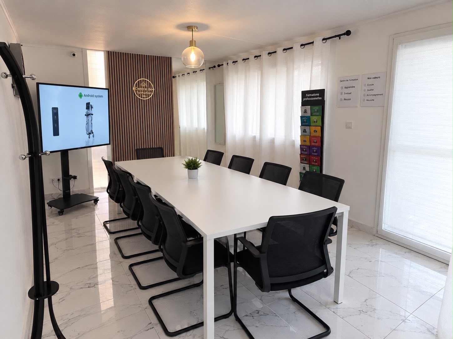 Salle de formation de notre institut de beauté partenaire à Montpellier : grande table, sièges et écran de présentation dans un espace lumineux.