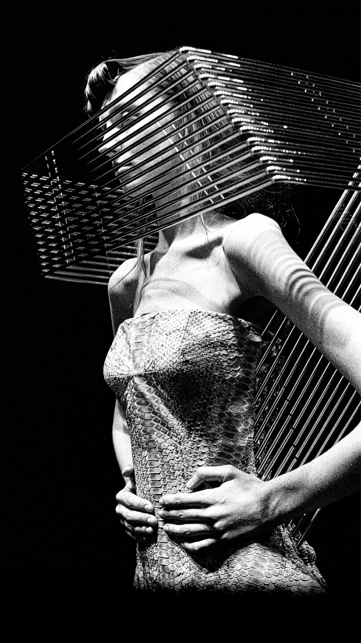 Black and white close-up of Shaun Leane’s archival Grille Collar, a geometric structured metal cage worn over a textured python skin bustier.