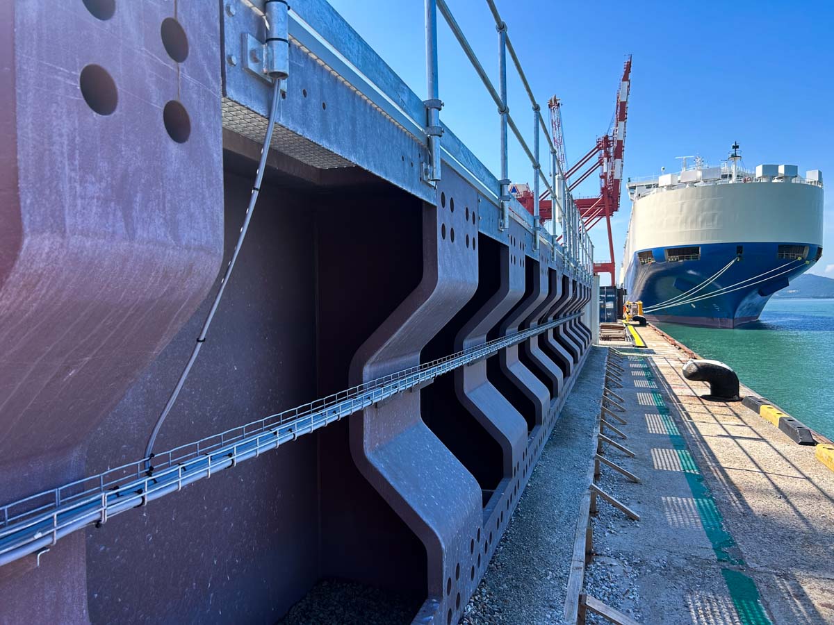 Large steel port structure alongside a dock with a vessel moored nearby