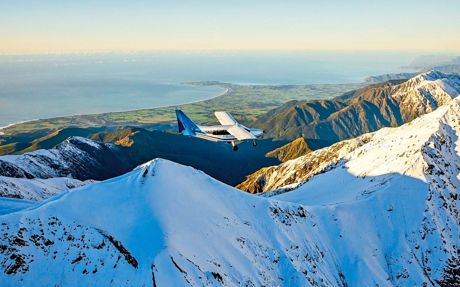 Luftaufnahme eines Flugzeugs, das über schneebedeckte Berge in Kaikoura, Neuseeland fliegt.