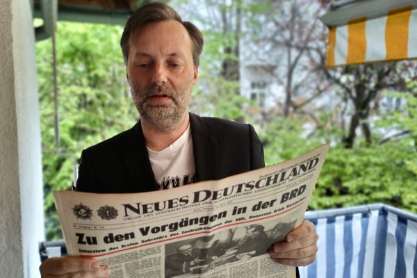 Daniel Häuser mit einer Zeitung aus dem Archiv