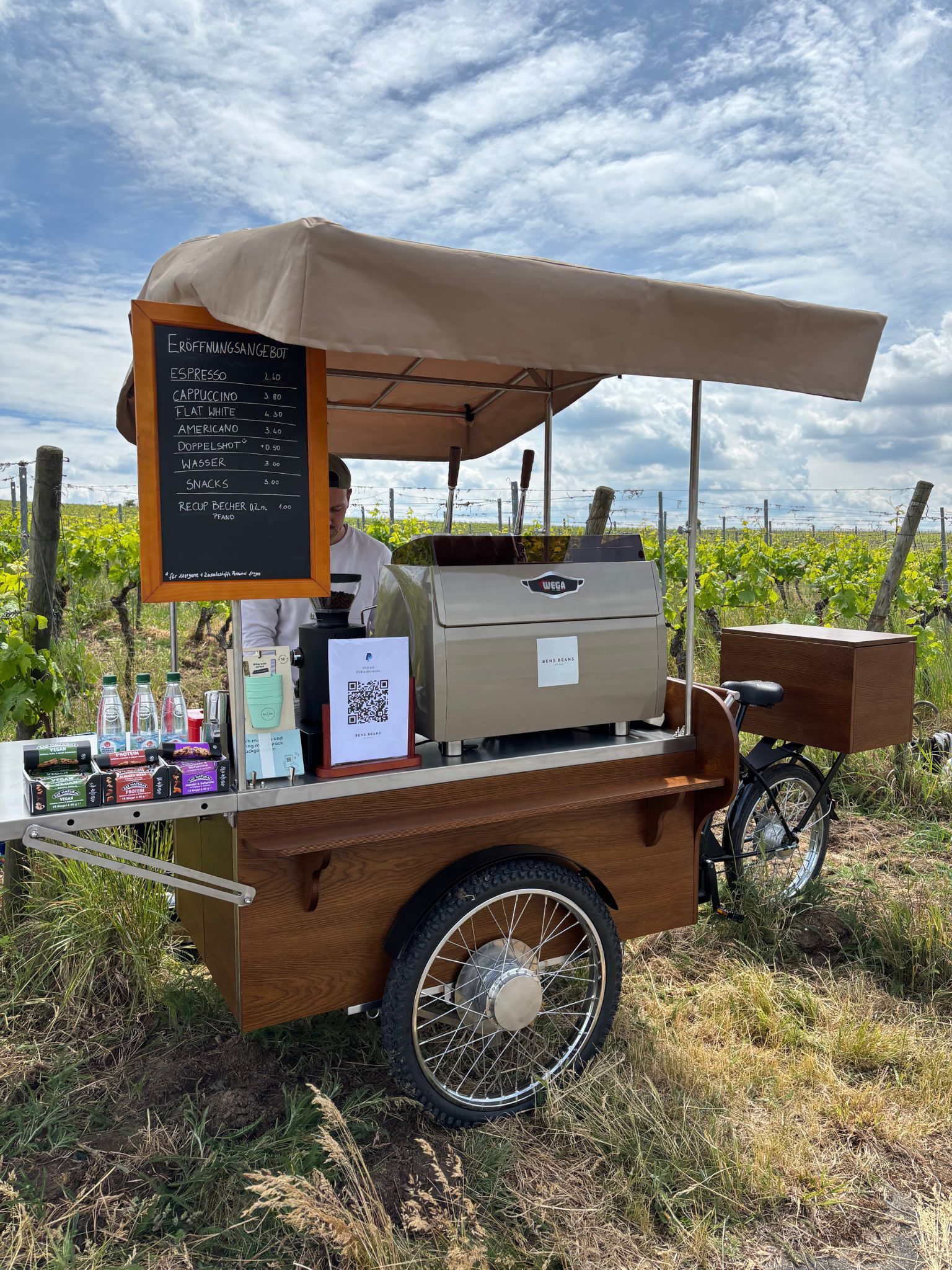 Kaffee-Fahrrad 'Bens Beans' inmitten von Weinbergen unter blauem Himmel, ein einzigartiges Highlight für eine freie Trauung im Freien.