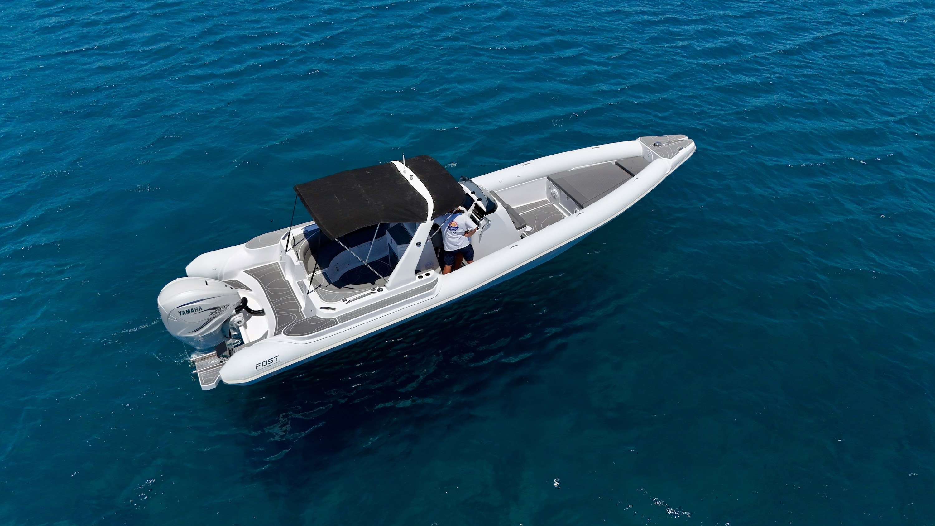 White Fost Matrix 32 speedboat with black T-top canopy cruising in crystal-clear turquoise waters of the Aegean Sea.