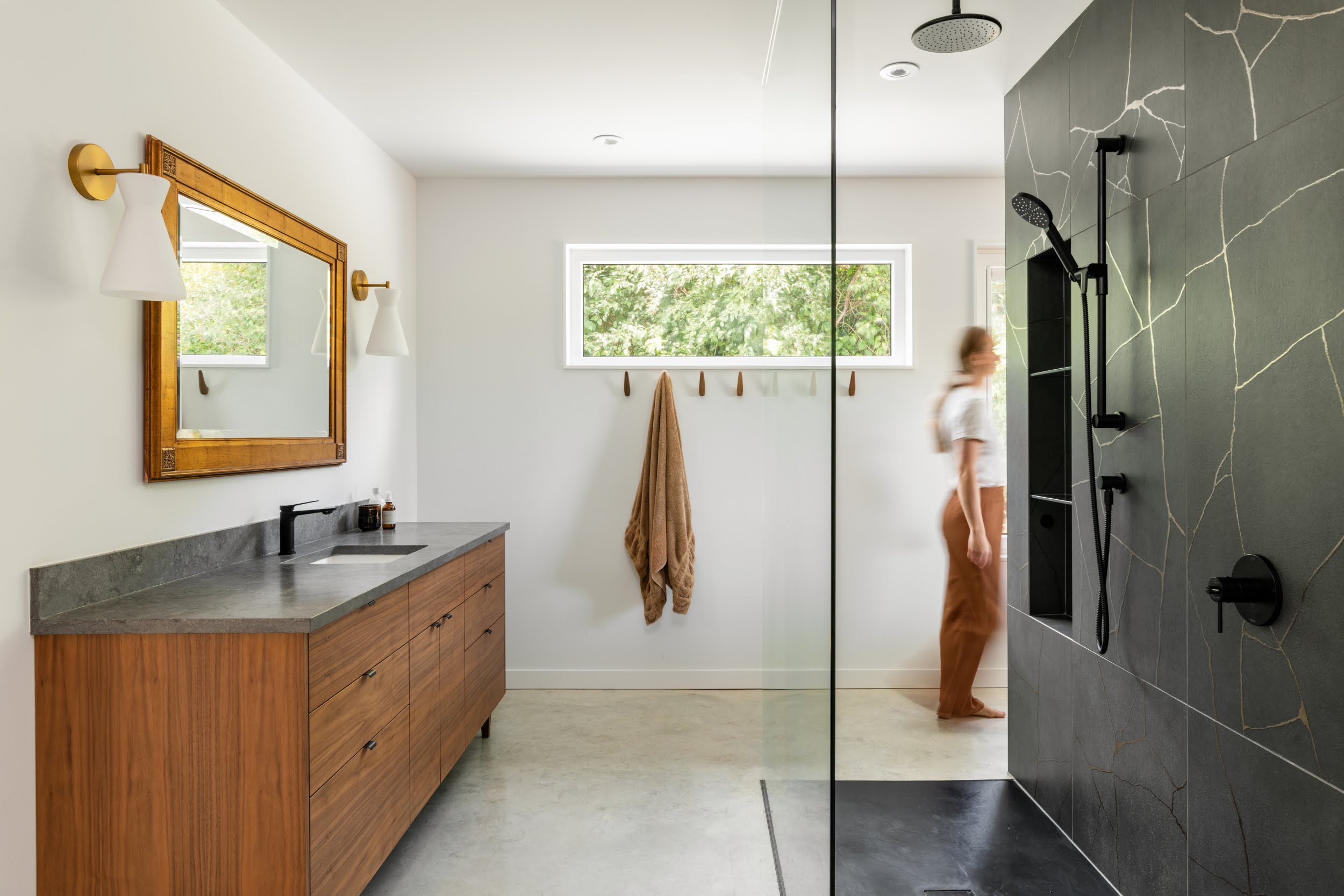 Modern living room with abstract art, beige sectional sofa, indoor plants, and large windows.