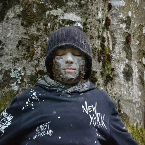 Ragazzo con viso mimetizzato nel bosco durante esperienza di connessione profonda con la natura
