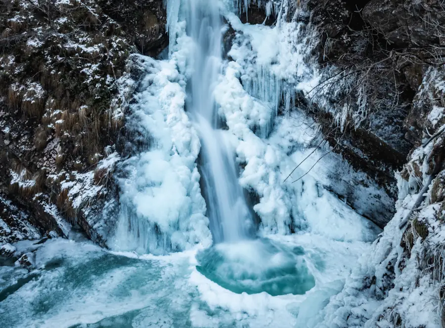 A partially frozen waterfall in Pekel Gorge near Borovnica, Slovenia, featuring cascading water flowing through a natural ice sculpture of thick white icicles and frosted rocks into a turquoise pool.