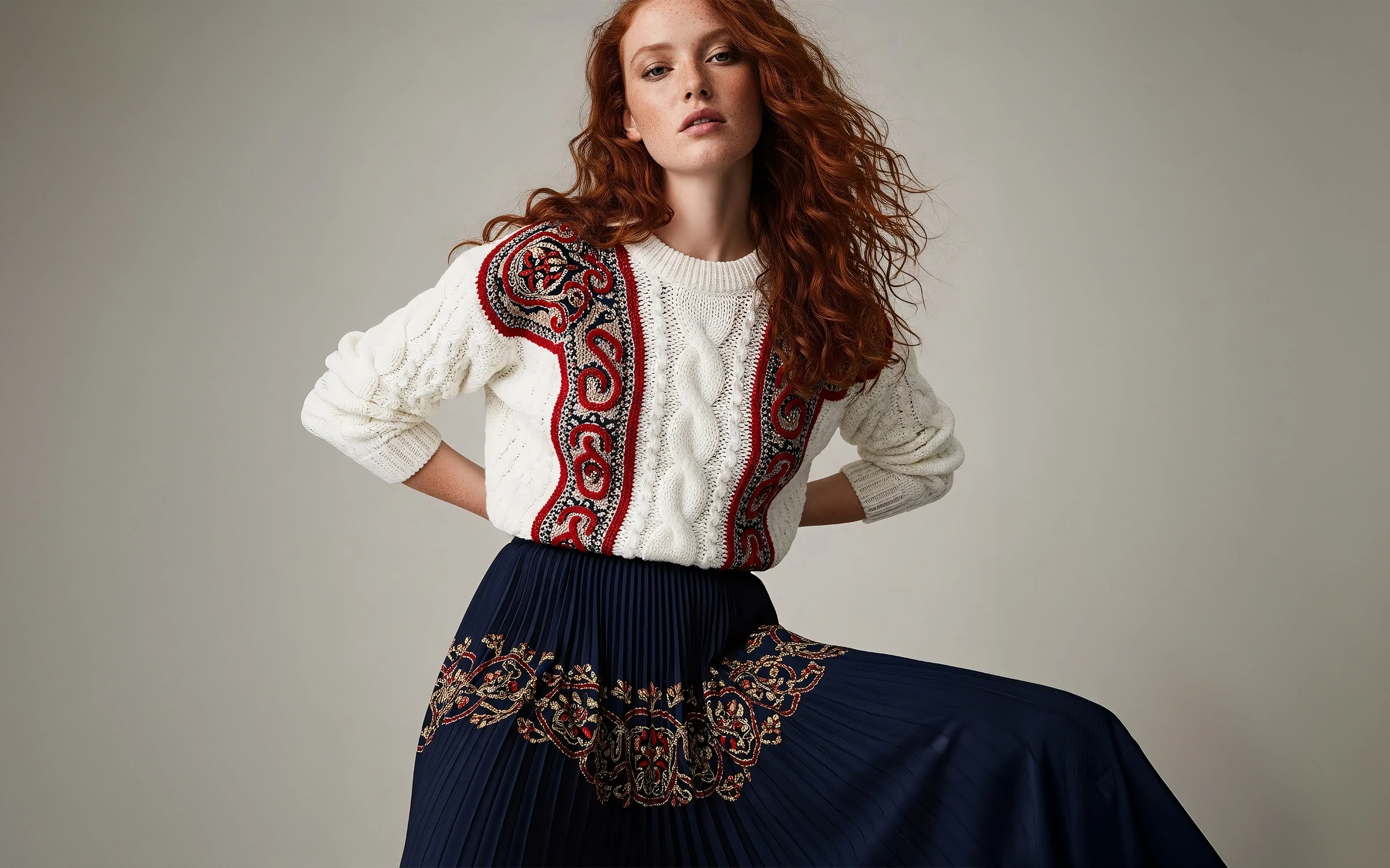 Stylish woman in white sweater, navy skirt with gold accents, poses confidently against neutral background.