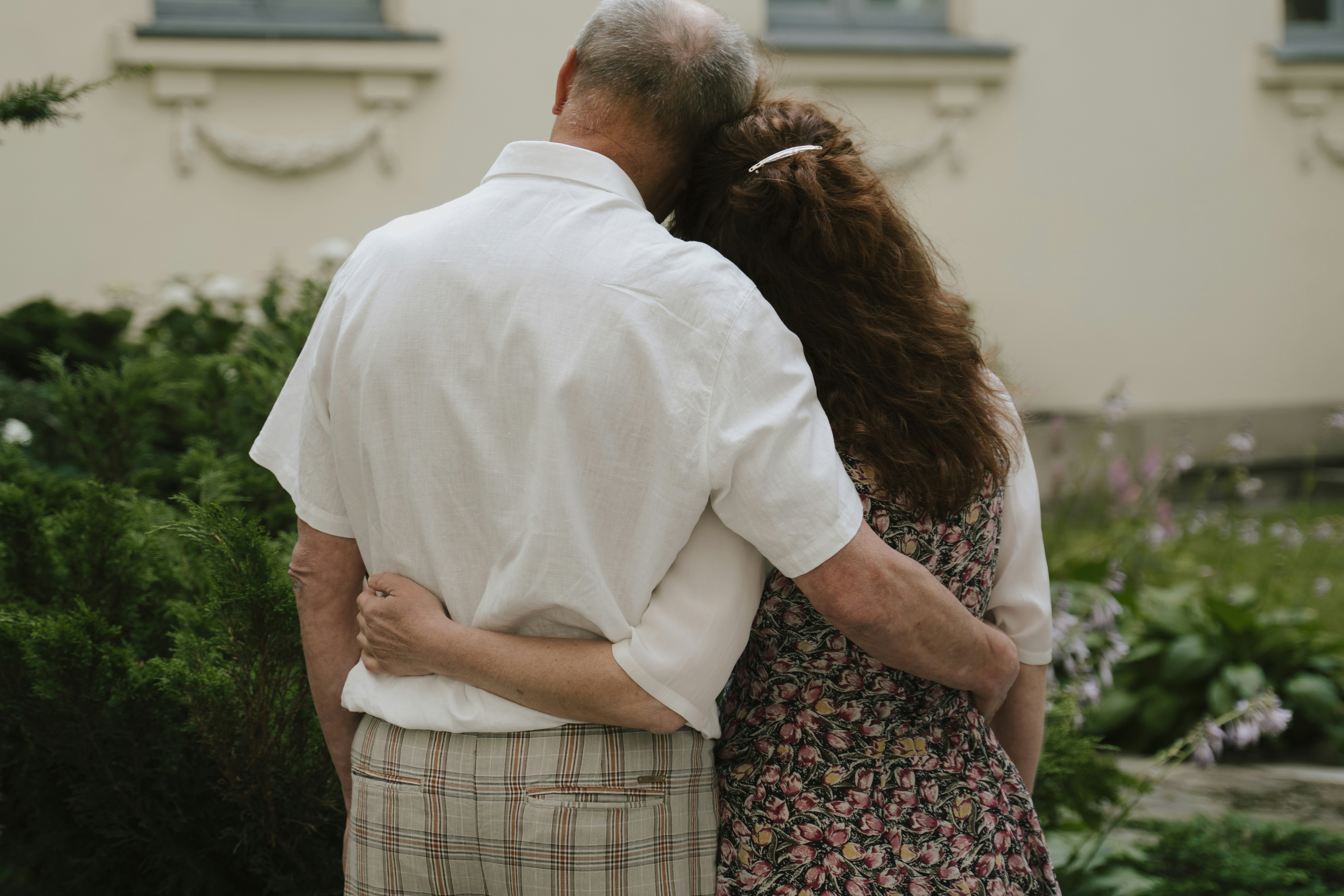 elderly man stands arm in arm with daughter