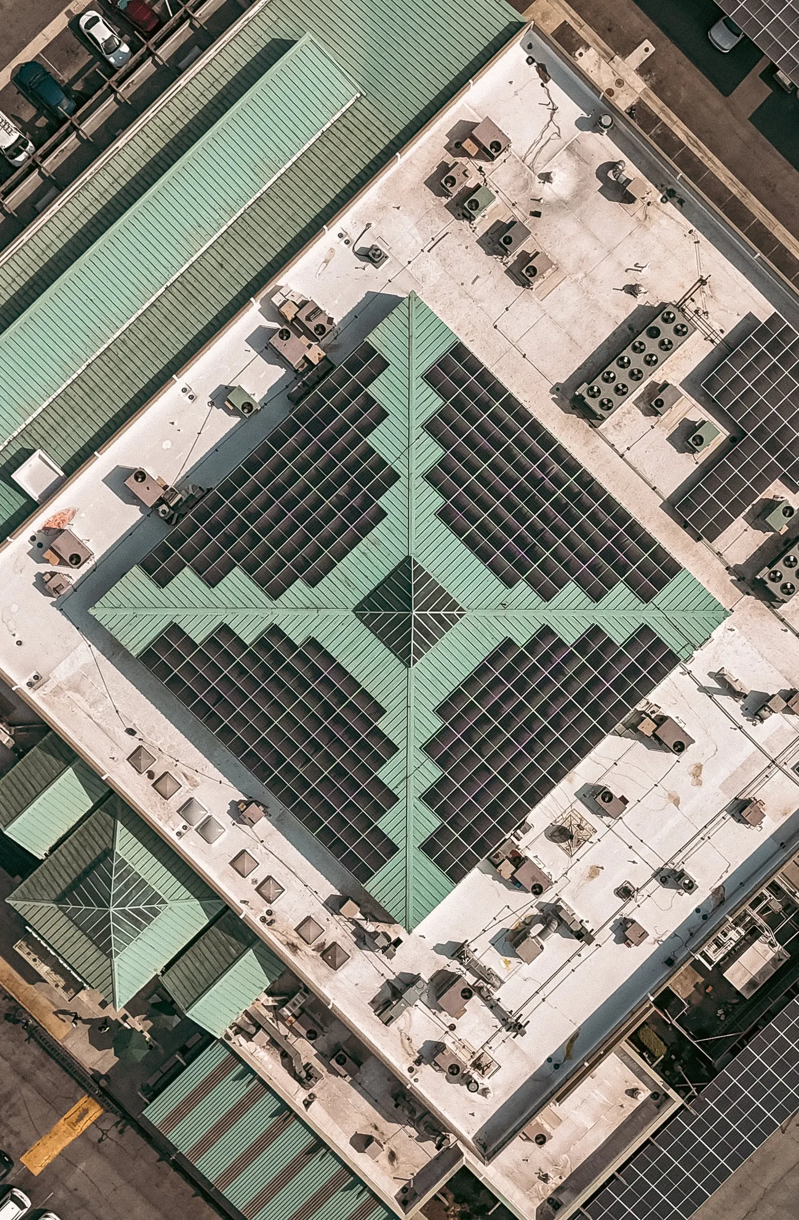 Overhead view of a commercial building roof filled with solar panels around its skylights