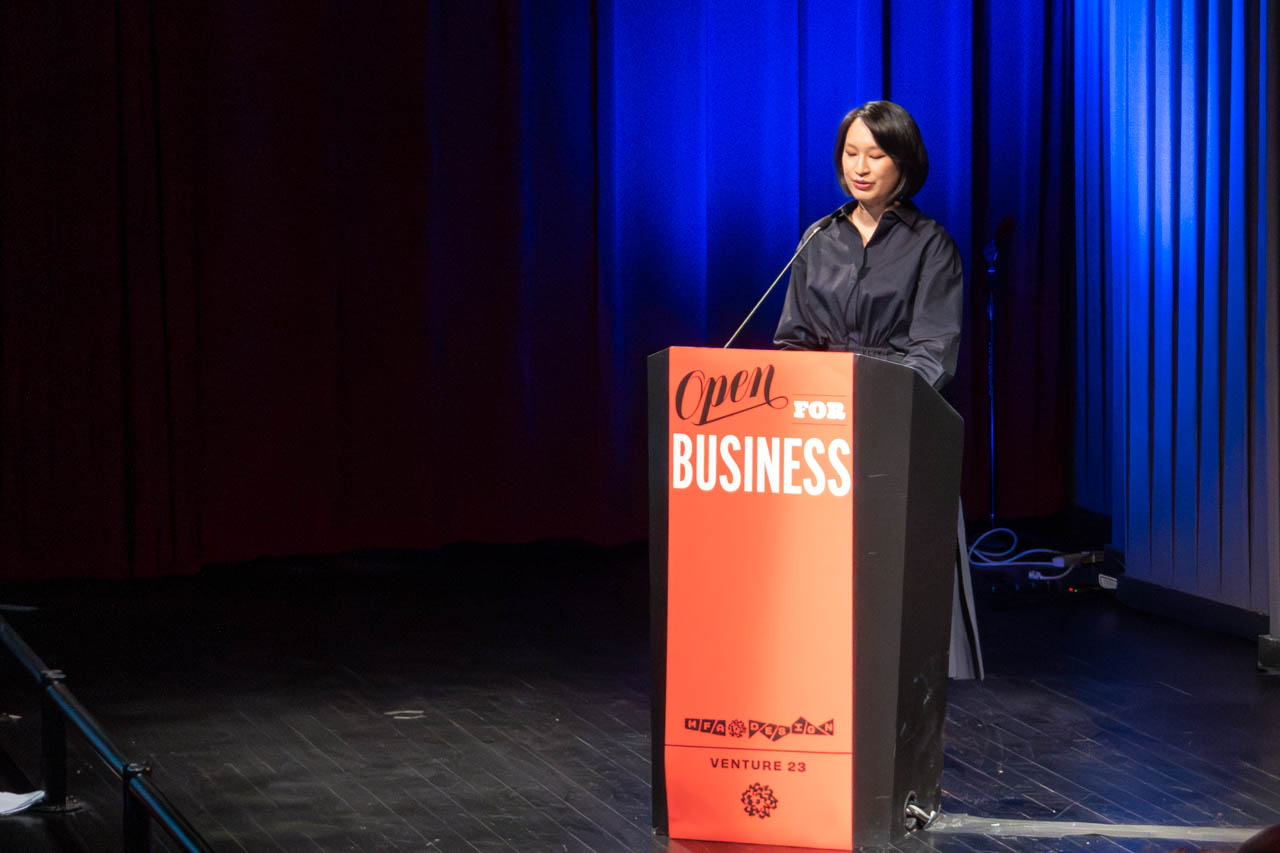 woman standing at a podium delivering a presentation