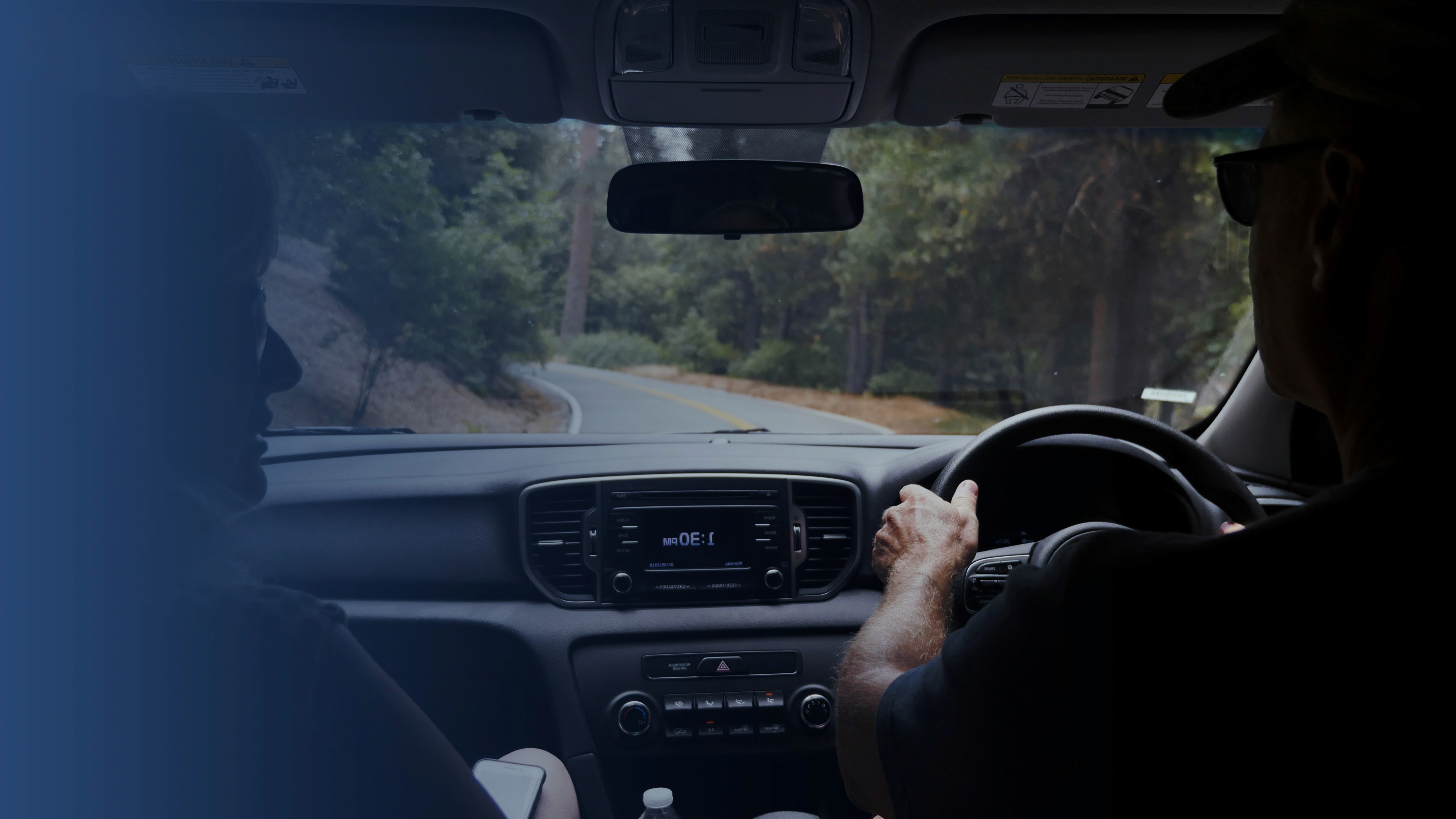 Woman placing a toddler into a car seat inside a car, representing safe driving for no claims bonus