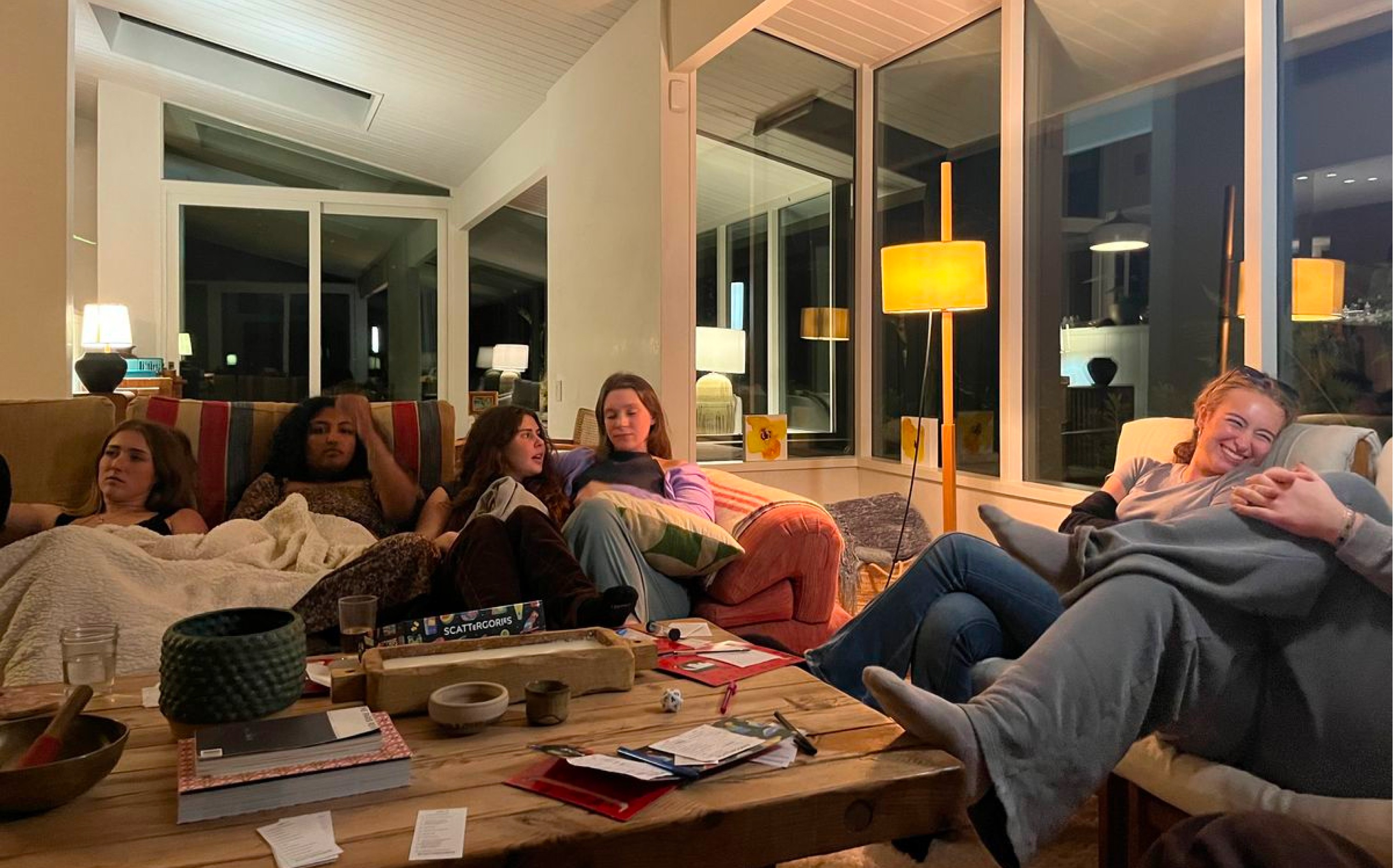 Group of friends laughing together during a break from their admin night tasks, notebooks still open on the table.