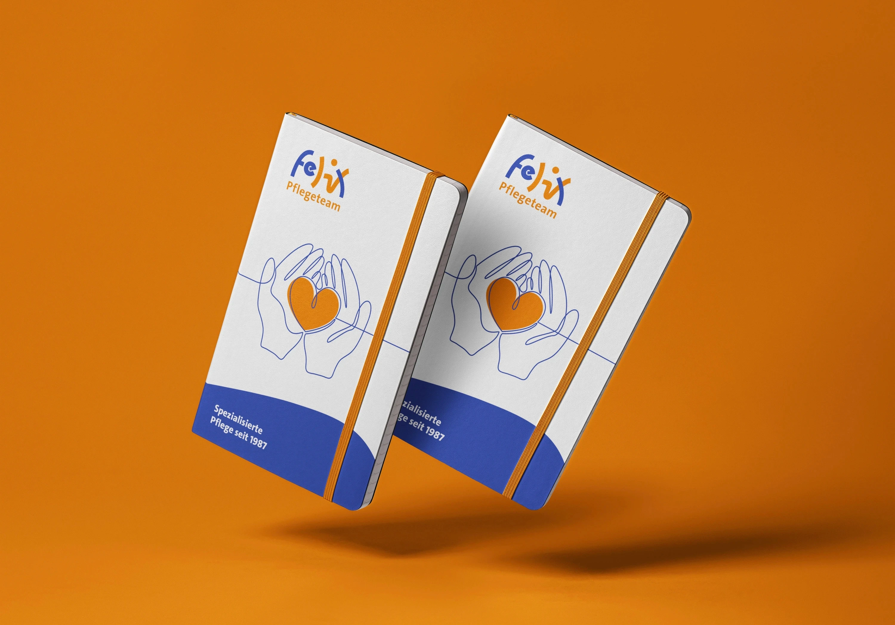 Felix Pflegeteam Notizbuch Mockup: zwei schwebende Notizbücher mit Herz-in-Händen-Logo, freigestellt auf orangem Hintergrund