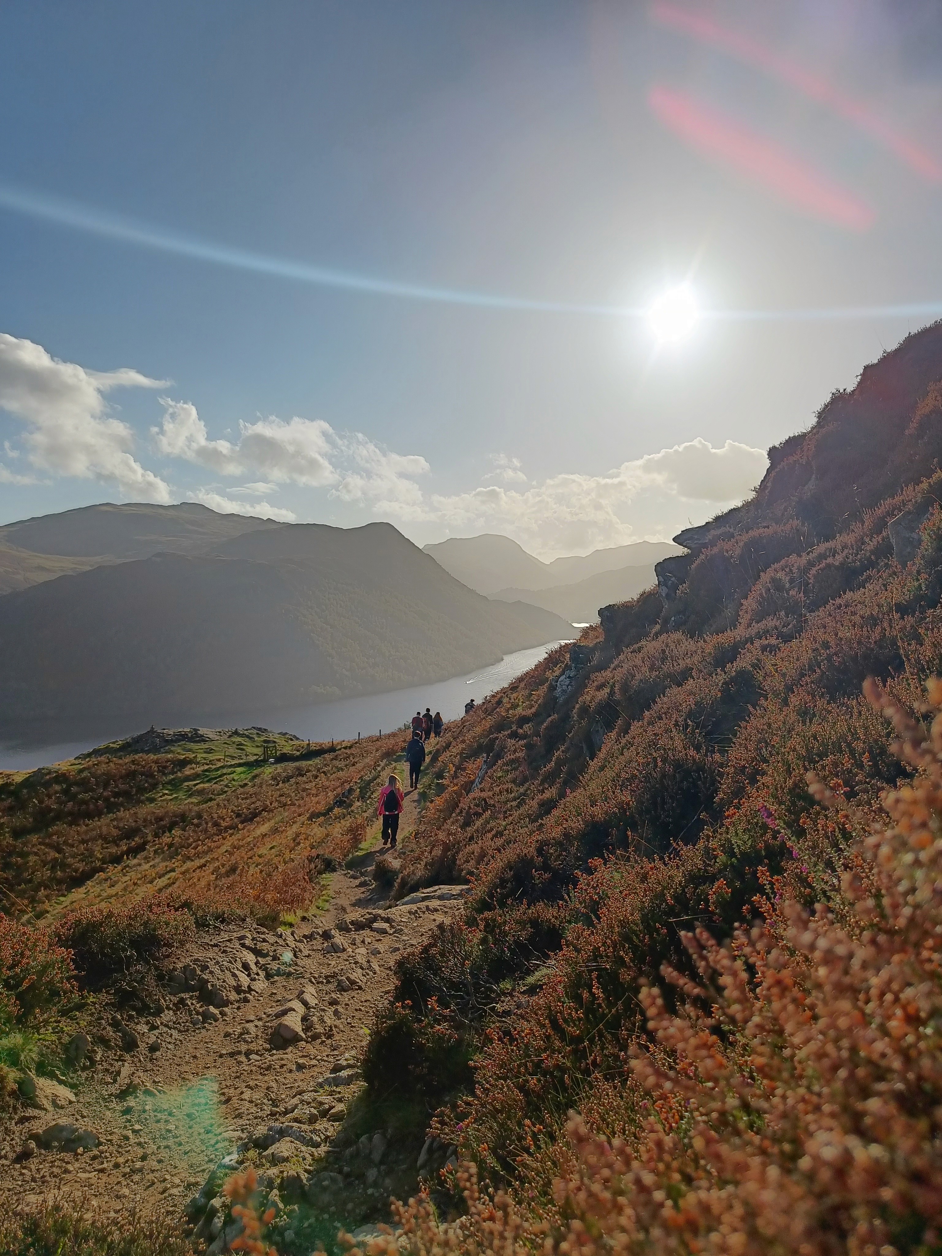 Hikers walking along a sunny mountain trail.