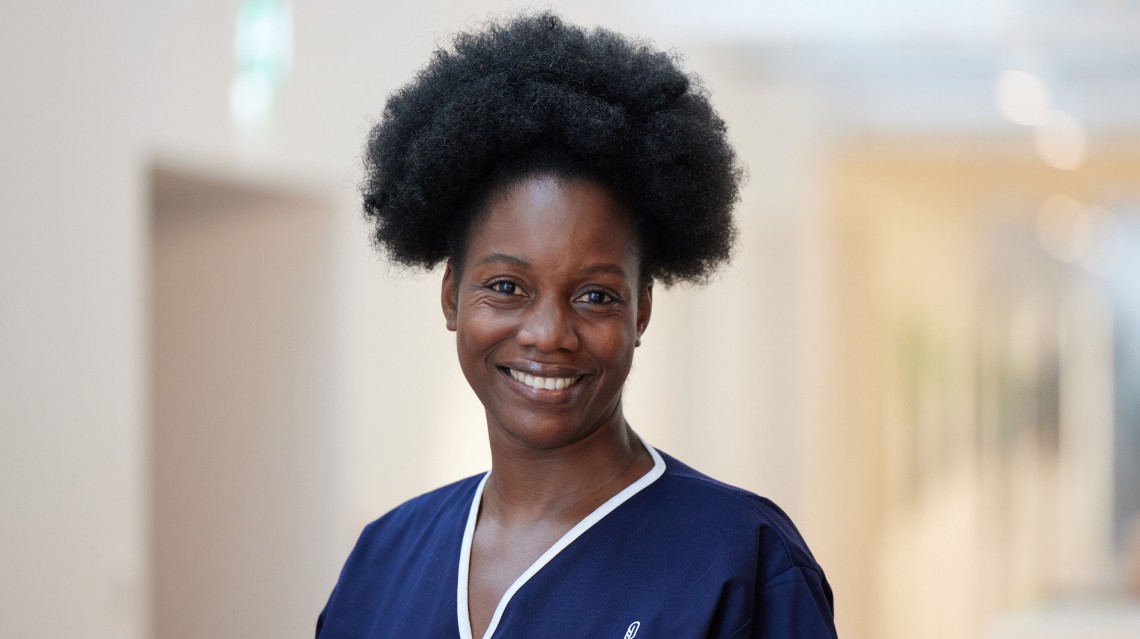 Smiling Florence healthcare worker standing in a softly lit hallway.
