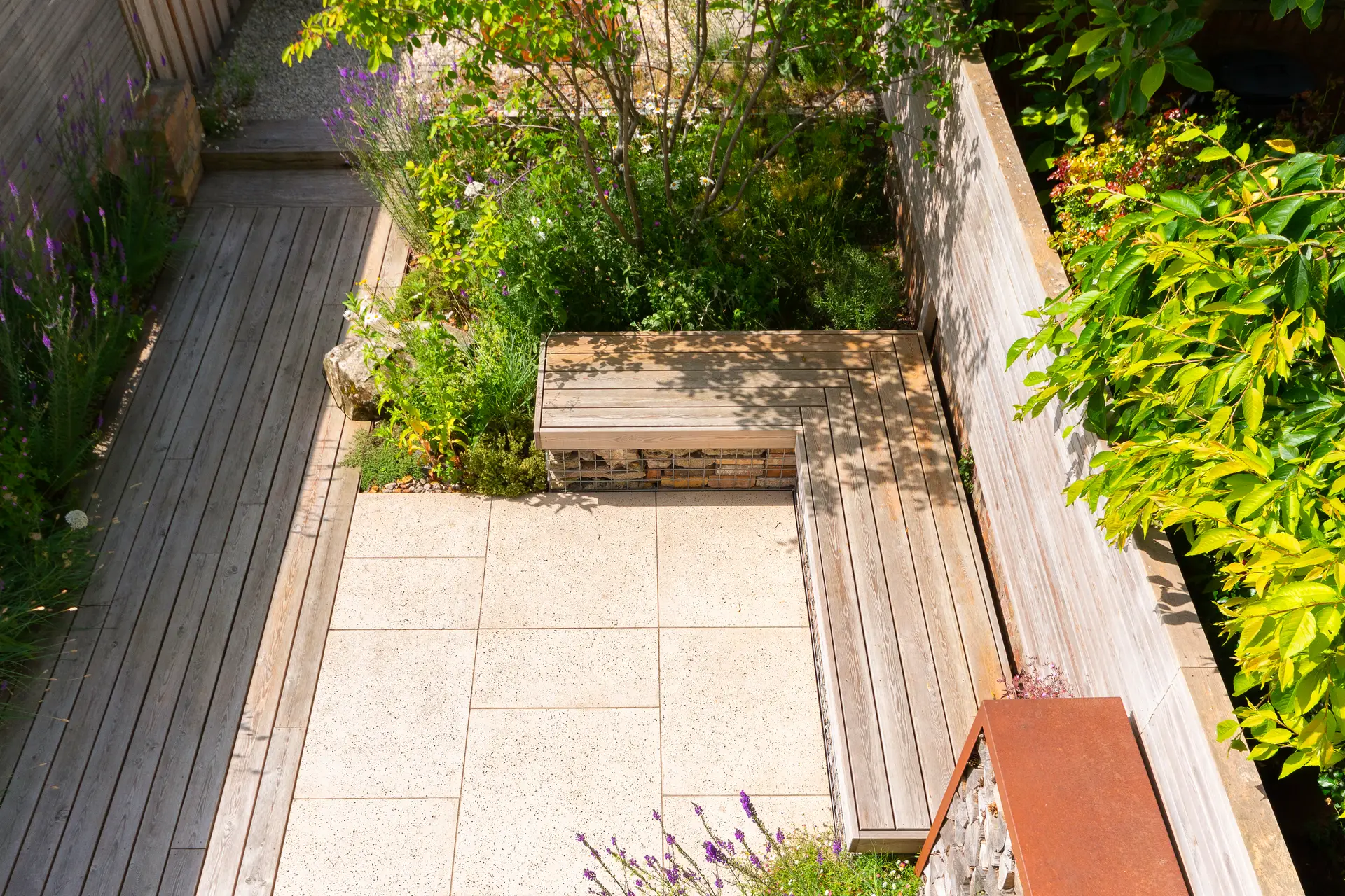 Aerial view of a garden with pathways, greenery, and a few raised beds showing a mix of plants and foliage.
