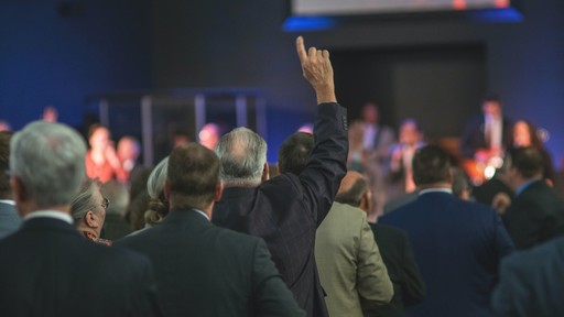 A person from the audience raising their hand to ask a question