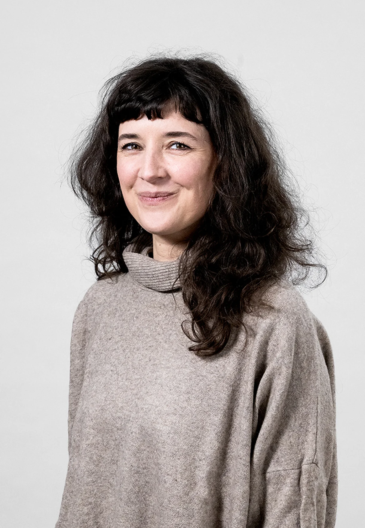 A person with curly hair sits at a desk, working on a laptop in a cozy, well-lit environment.