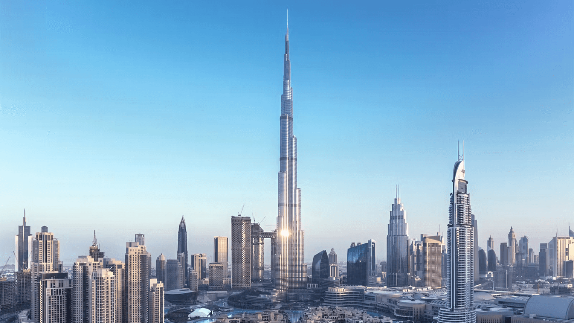 The Dubai skyline against a bright blue sky with the towering Burj Khalifa in the center of the photo.